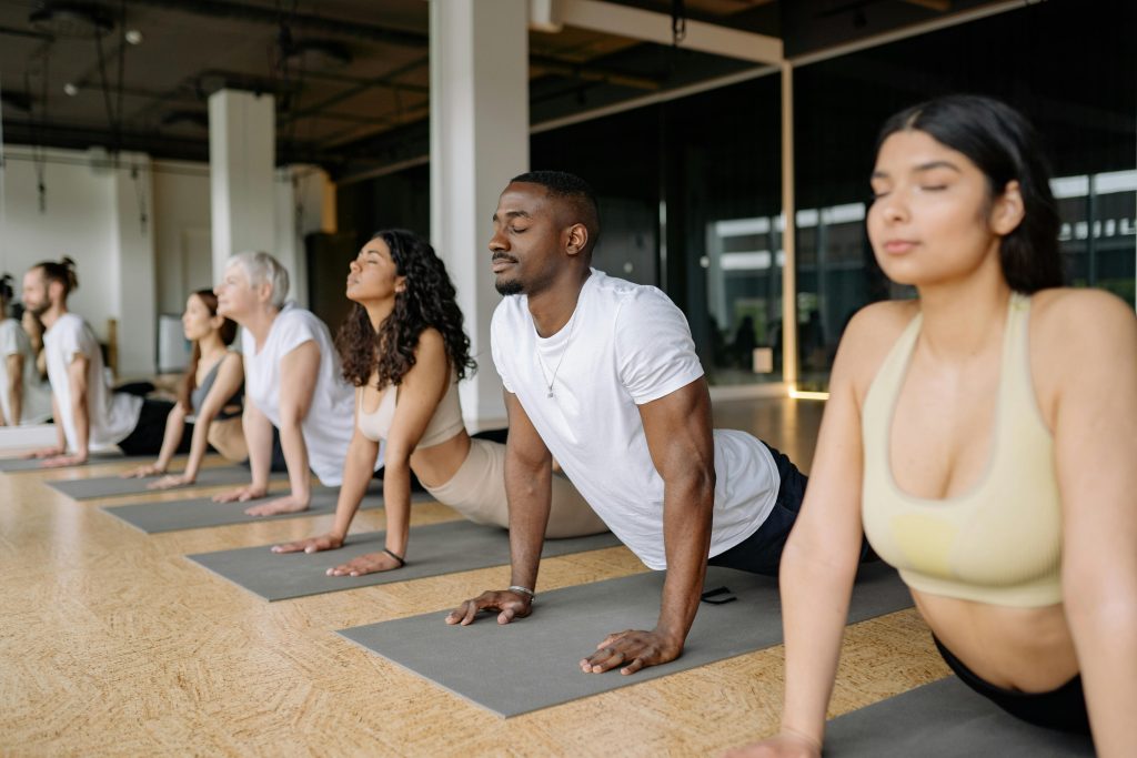 A diverse group of adults practicing yoga poses in a light-filled studio.