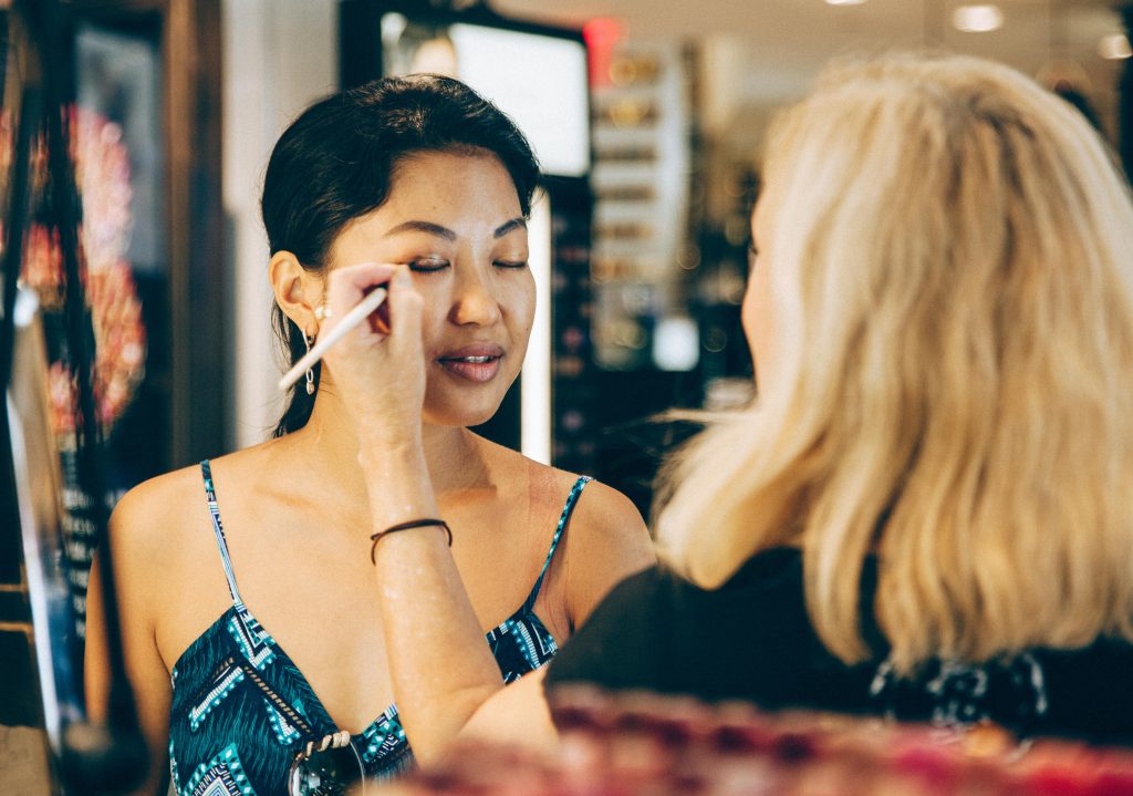 A makeup artist expertly applying cosmetics to a woman in a stylish New York City salon.