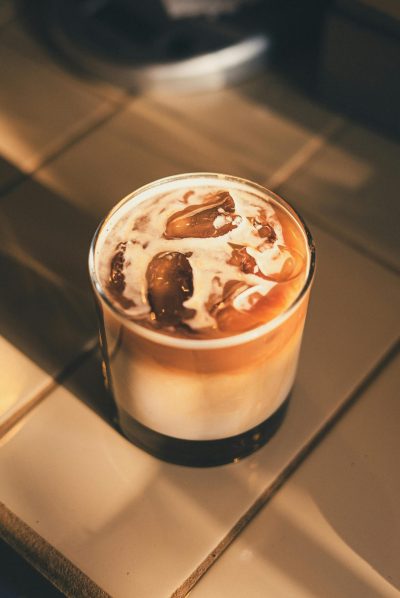 A refreshing iced coffee with cream served on a sunny countertop.